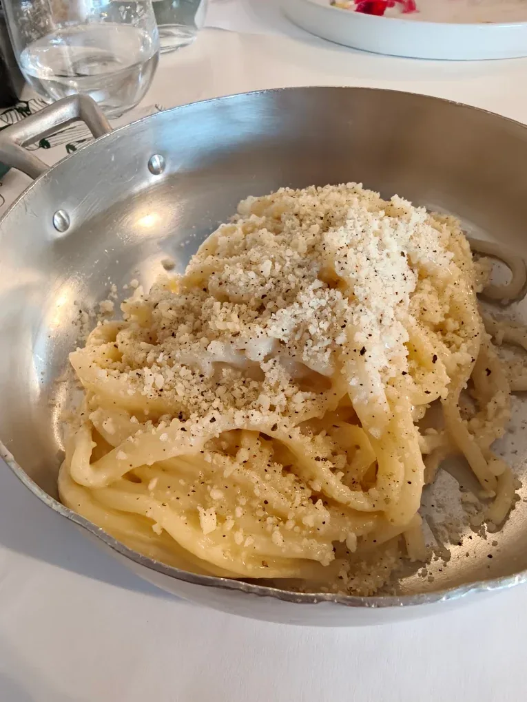 Cacio e pepe nel tegamino di alluminio con pecorino grattugiato e pepe nero