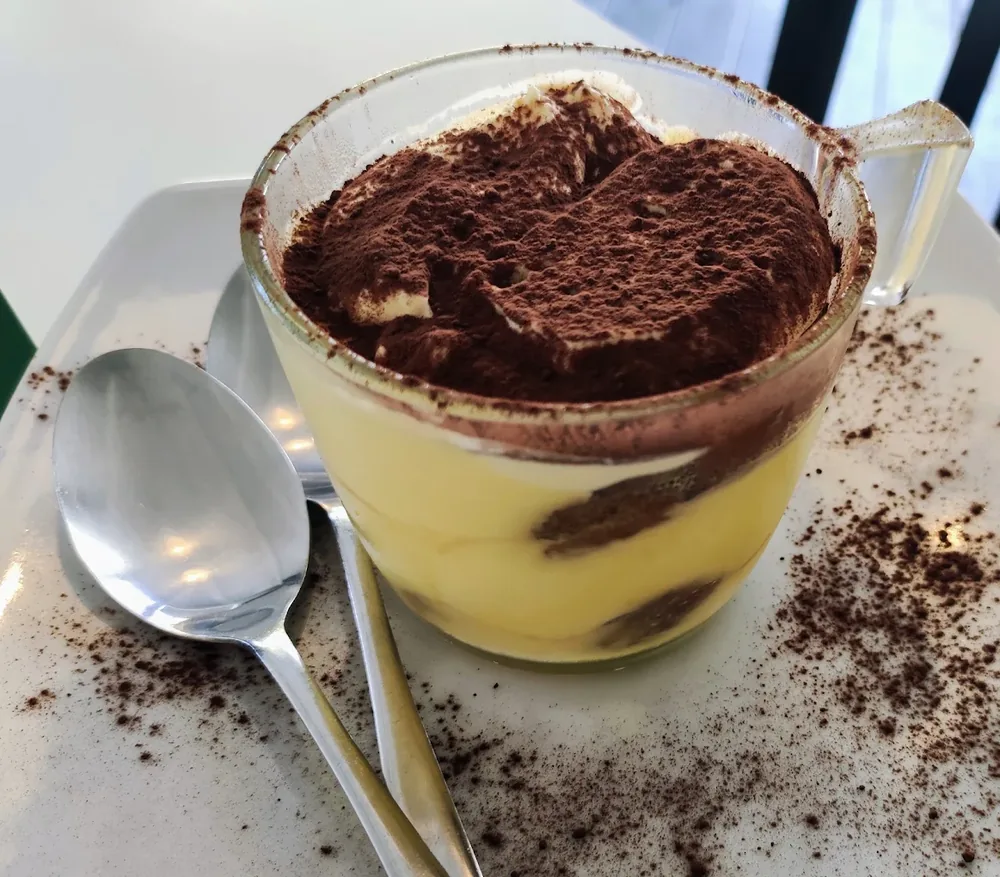 Tiramisù servito nella tazza di vetro con cacao in polvere